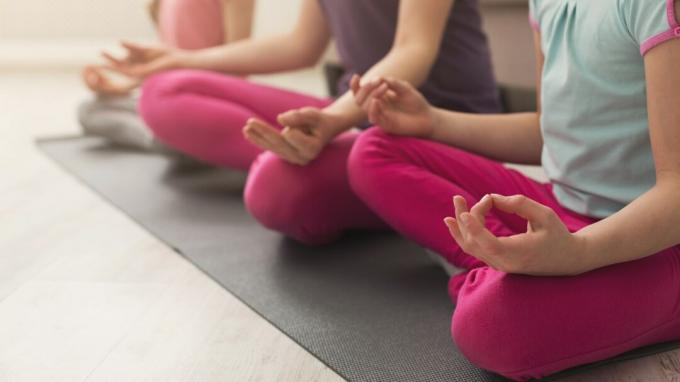 Nahaufnahme der Hände der Mutter und der Töchter, die Yoga-Übung machen und zu Hause dehnen. Gesundheits-, Sport-, Freizeitkonzept